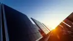 Bild på uppmonterade solceller på rad i solnedgång
